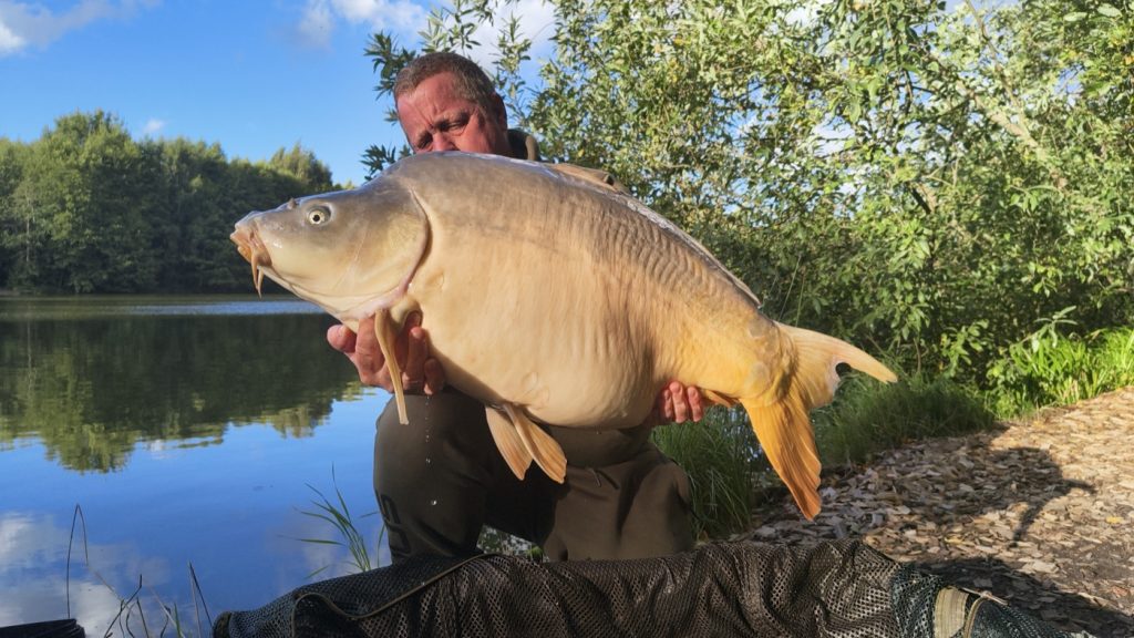 Carp Addict Clothing owner on the bank with a mirror carp