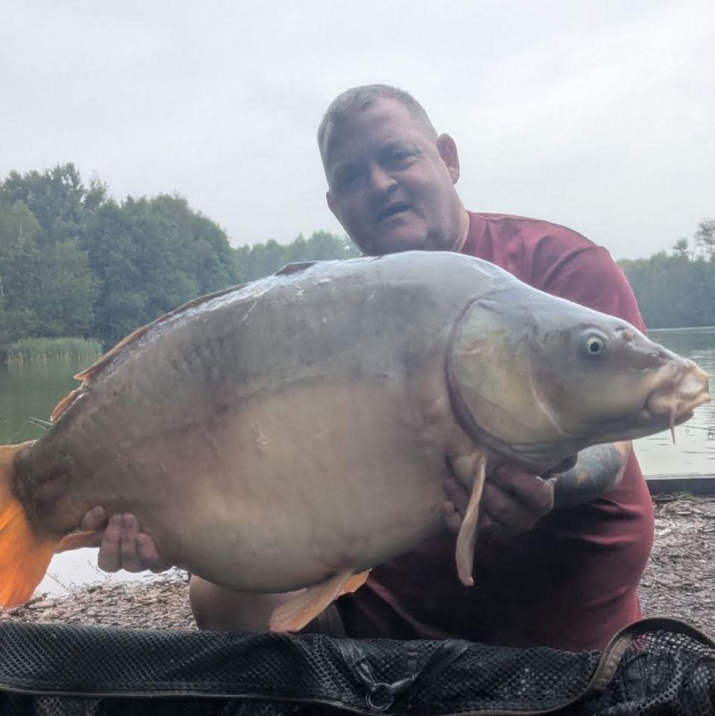 Carp Addict Clothing owner on the bank with a mirror carp